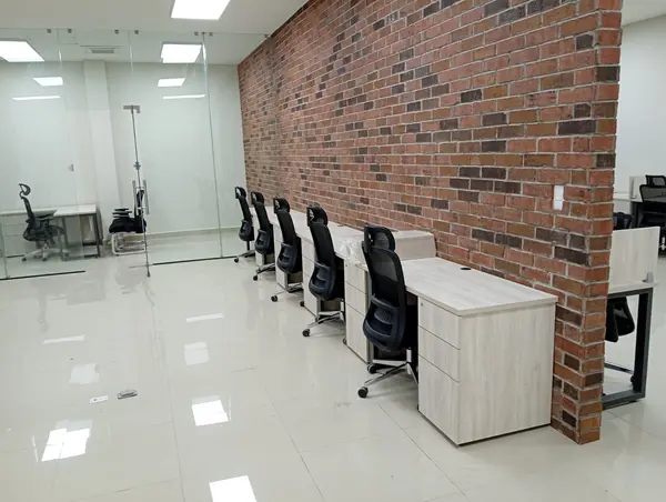 Estaciones de trabajo frente a una oficina privada de cristal equipadas por Ofichap